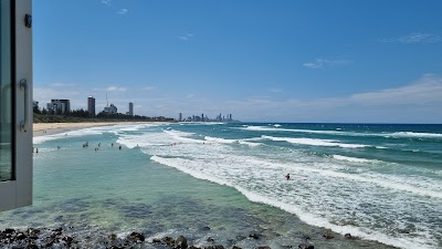 バーリー・ヘッズの岬と波打ち際のサーファー